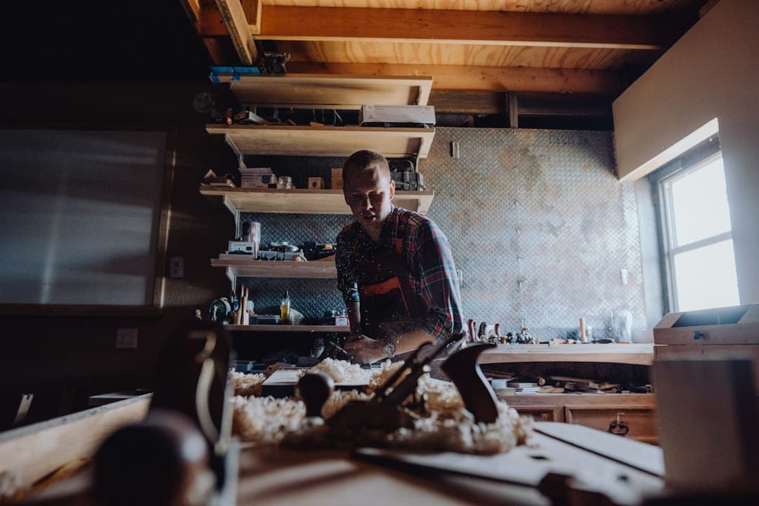 A woodworker shaping a component at a bench in a woodworking shop.